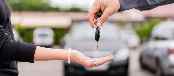 Un hombre entrega las llaves de un carro a una mujer