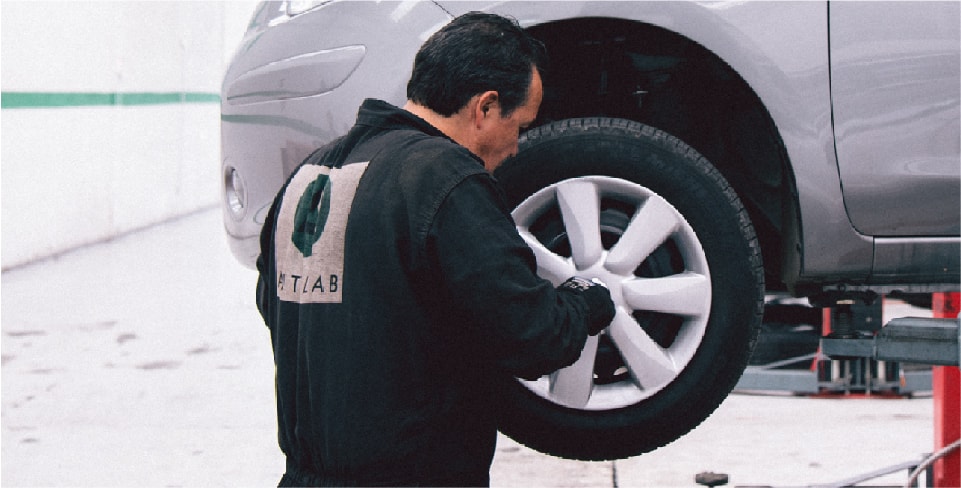 Hombre en un taller mecánico comprobando el balanceo de un carro