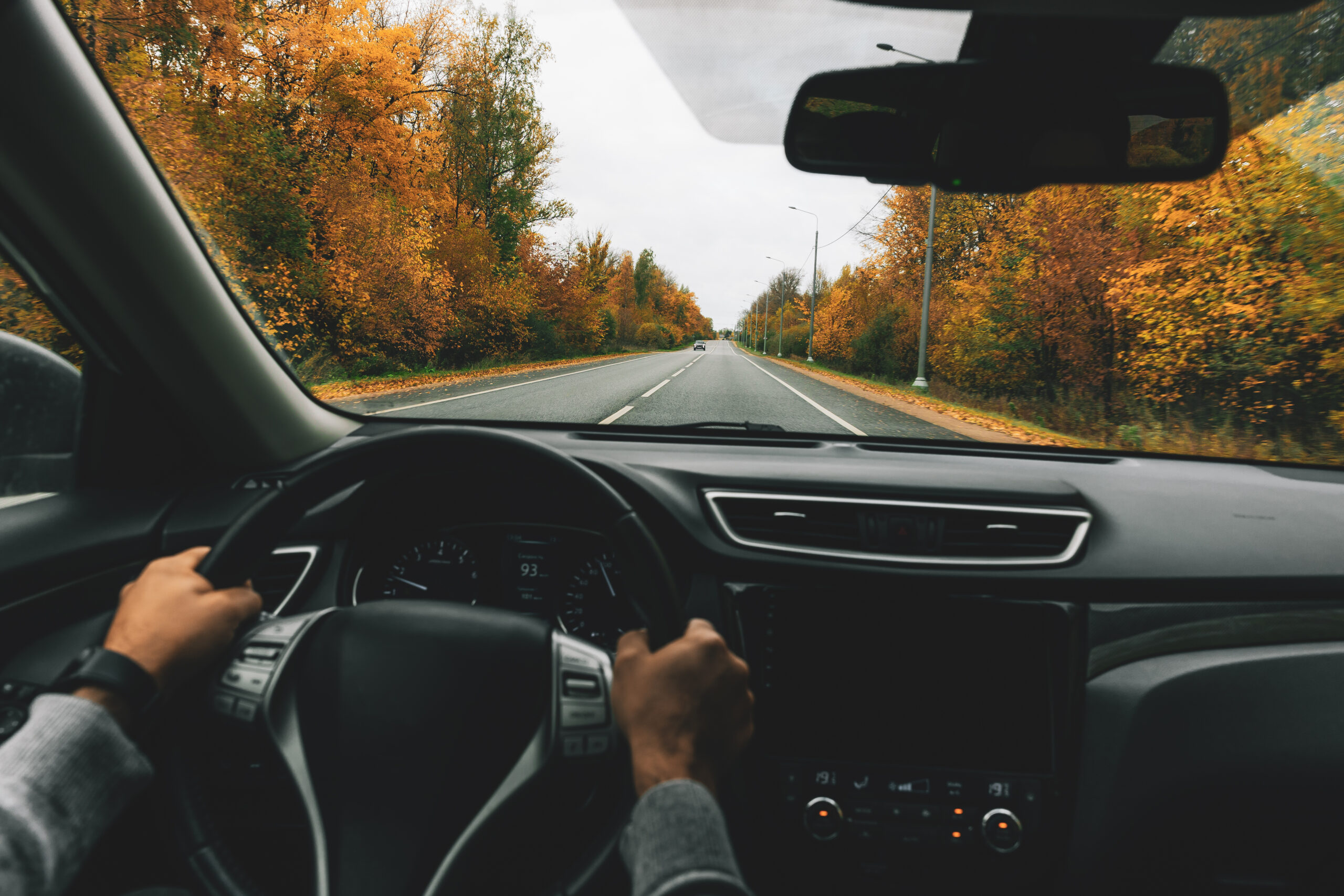Man driving car on the country road in autumn.
